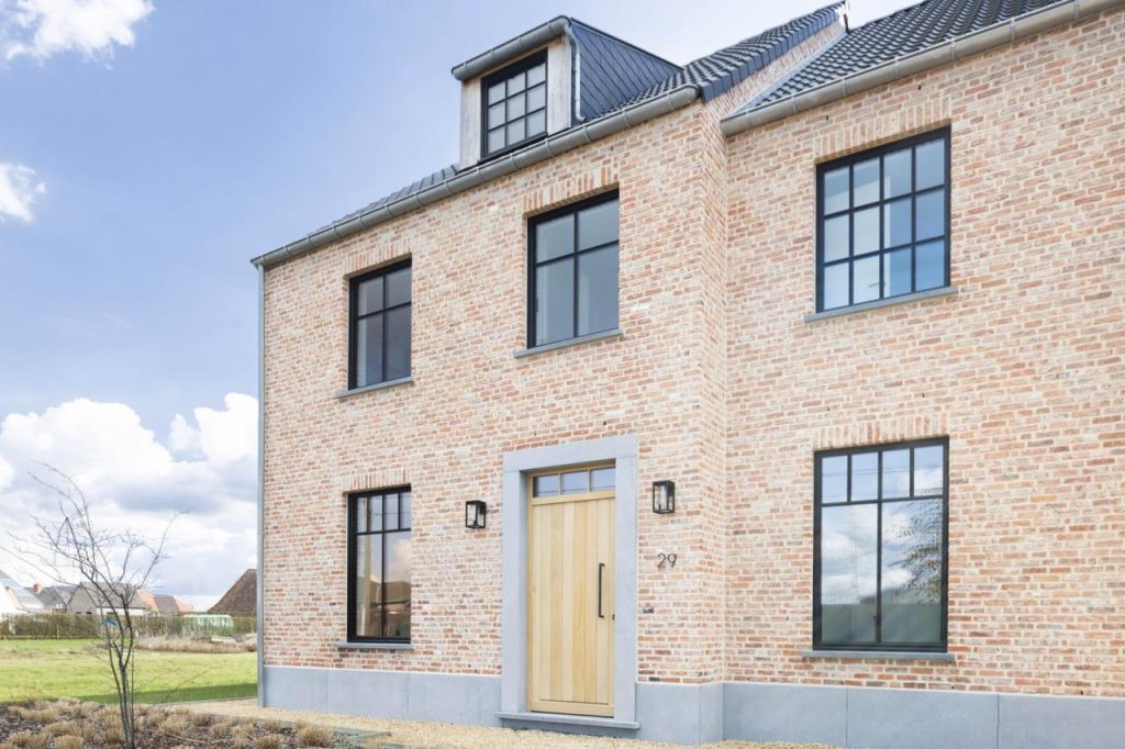 Moderne woning met grote aluminium ramen en deuren die elegant aansluiten op de tuin, demonstrerend waarom aluminium ramen en